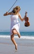 young happy woman jump on beach with a violin young happy woman jump on beach with a violin