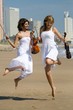 two young women jump on beach with violins two young women jump on beach with violins
