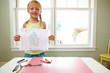 Cute girl standing by table with drawing paper