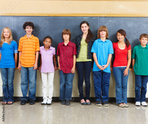 Photo: Portrait of students standing in a classroom with blackboard in Portrait of students standing in a classroom with blackboard in
