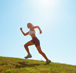 Foto: Woman jogging on a grassy land on a sunny day Woman jogging on a grassy land on a sunny day