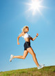 Foto: Woman jogging on a grassy land on a sunny day Woman jogging on a grassy land on a sunny day