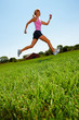 Foto: Woman jogging on a grassy land Woman jogging on a grassy land