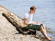 Man using laptop near stream