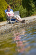 Woman using laptop near stream