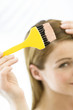 Portrait of a young woman dyeing her hair, little brush in her hand