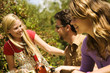 2 young women and a man sitting at garden table