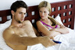 Young couple in bed, watching TV