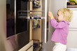 Little girl opening cabinets in kitchen, indoors
