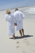 Couple in bathrobe walking on the beach, rear view