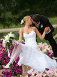 Newlywed couple kissing on flower bed