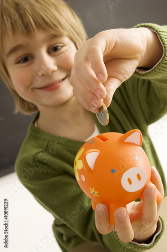 Photo: Boy putting a coin into a piggy bank Boy putting a coin into a piggy bank