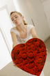 Young woman holding a heart shape gift and puckering her lips