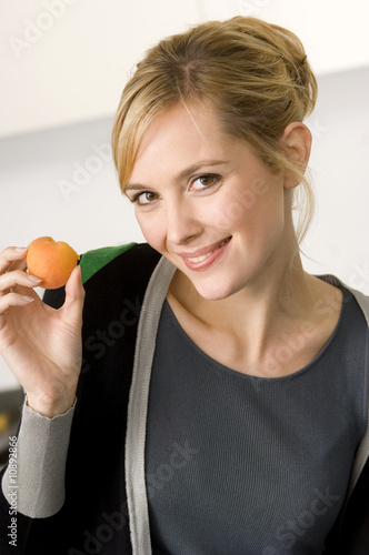 Photo: Portrait of a young woman showing an apricot Portrait of a young woman showing an apricot
