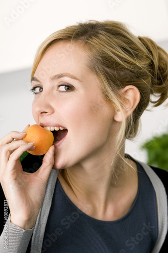 Photo: Portrait of a young woman eating an apricot Portrait of a young woman eating an apricot