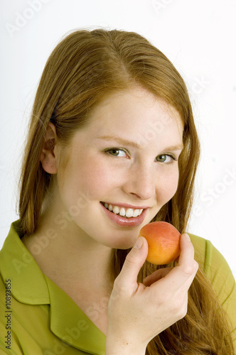 Photo: Portrait of a young woman eating an apricot and smiling Portrait of a young woman eating an apricot and smiling