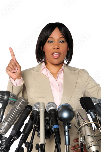 Photo: Woman Speaking Behind Microphones Woman Speaking Behind Microphones