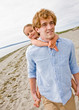 Father giving daughter piggy back ride at beach