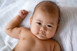 Baby lying on bed, looking straight at camera Baby lying on bed, looking straight at camera