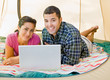 Couple laying in tent using laptop