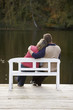 couple sitting on a bench at a lake in autumn