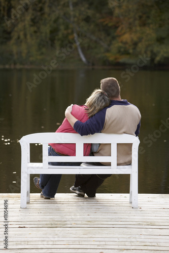 Photo: couple sitting on a bench at a lake in autumn couple sitting on a bench at a lake in autumn