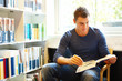 Handsome man sitting and reading in library