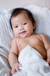 Smiling baby in bed under blanket Smiling baby in bed under blanket