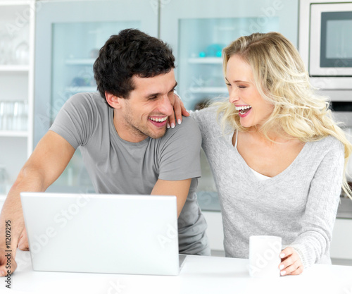 Foto: Young couple having fun while using a laptop Young couple having fun while using a laptop