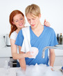 Photo: Young couple doing dishes together Young couple doing dishes together