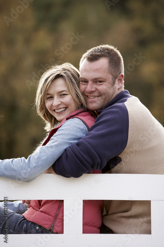 Photo: couple sitting on a bench at a lake in autumn couple sitting on a bench at a lake in autumn