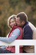 couple sitting on a bench at a lake in autumn