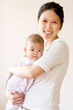 Smiling mother embracing baby. High key image.
