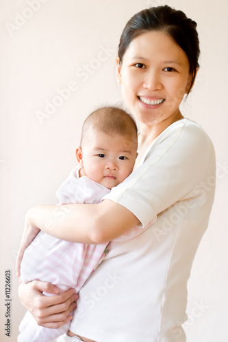 Foto: Smiling mother embracing baby. High key image. Smiling mother embracing baby. High key image.