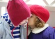 Children, winter red hat whispering in ear Children, winter red hat whispering in ear