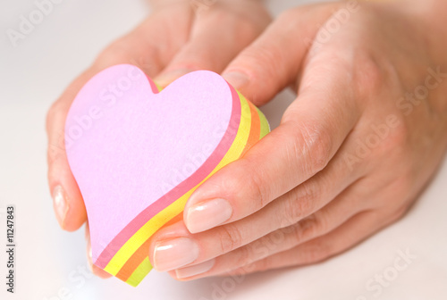 Photo: Hands holding heart shaped colorful sticky notes Hands holding heart shaped colorful sticky notes