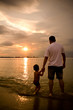 Foto: Father and son on the beach holding hands during sunset Father and son on the beach holding hands during sunset