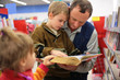Grandfather and grandson and girl read the book in bookshop
