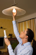 Young woman changes in energy-saving light bulb lamp