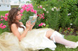 girl with book in hand under rosebushes