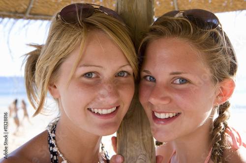 Foto: Teenage girls posing under beach umbrella Teenage girls posing under beach umbrella