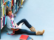 Female student sitting by bookshelf with books in the library Female student sitting by bookshelf with books in the library