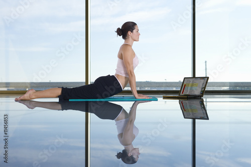 Photo: Woman doing yoga next to laptop Woman doing yoga next to laptop