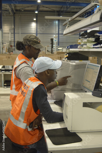 Photo: Warehouse operatives checking computer Warehouse operatives checking computer