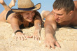 young girl and man lay on sand young girl and man lay on sand