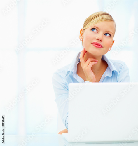 Closeup of a young woman using laptop with her hand on neck