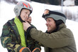 Father helping son with ski helmet
