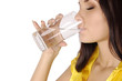 Beautiful young girl drinks water from glass