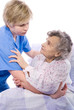 nurse helps the senior woman get up
