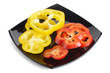 Slices of red and yellow pepper on a black plate